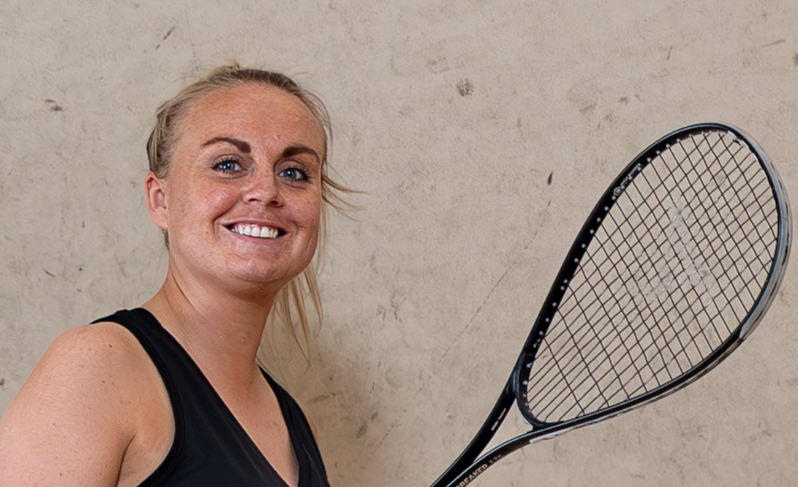 Close-up van een lachende vrouw met squashracket bij Dekker Warmond.