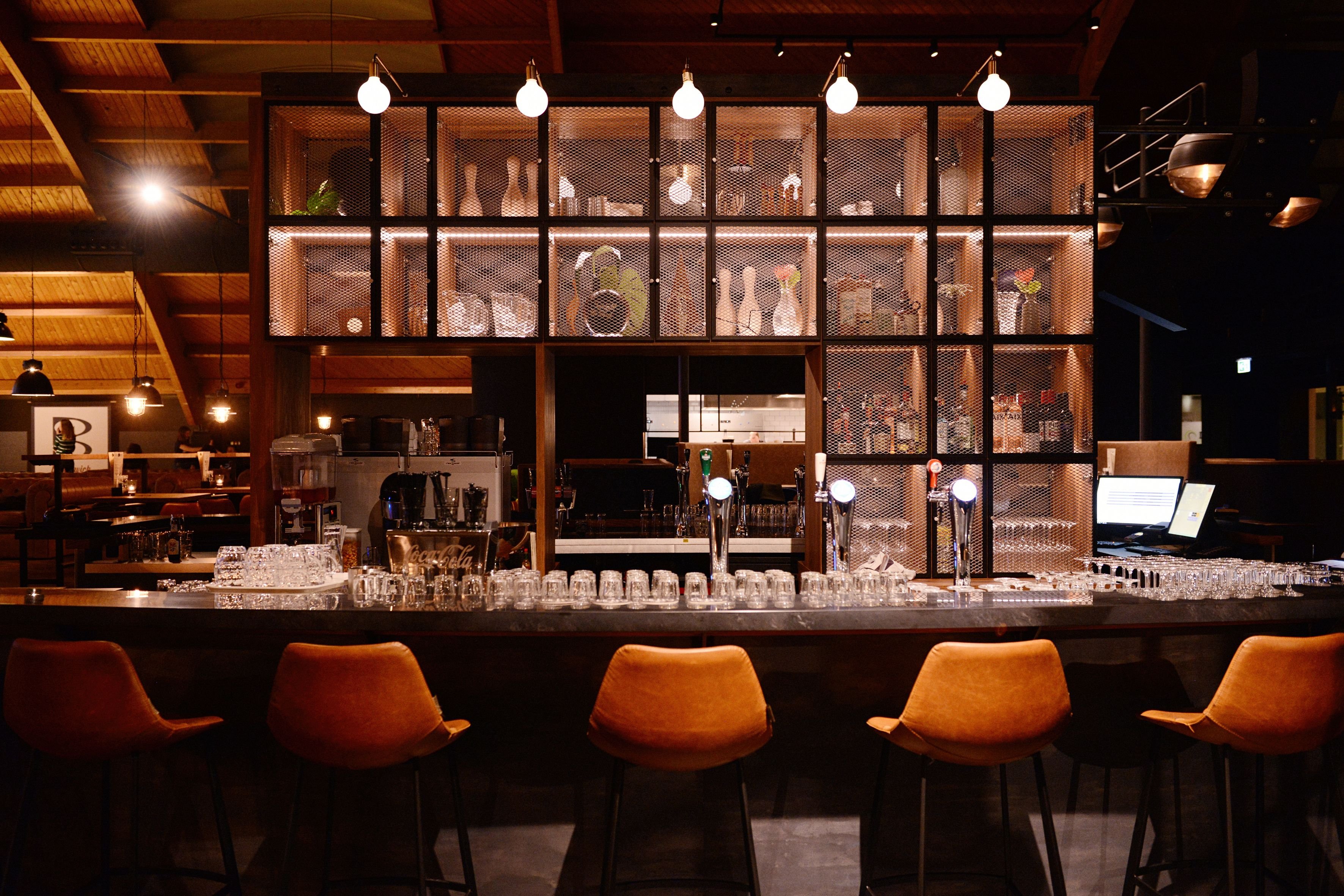 Sfeervolle bar bij Lucky’s Bowling in Dekker Warmond met warme verlichting, comfortabele barkrukken, houten interieur en een uitgebreide bar met biertaps.