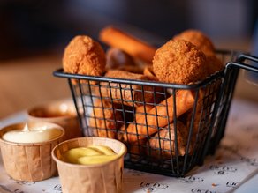 Close-up van een mandje met krokante bitterballen en andere warme borrelhapjes, geserveerd met verschillende dipsauzen bij Lucky’s in Dekker Warmond.