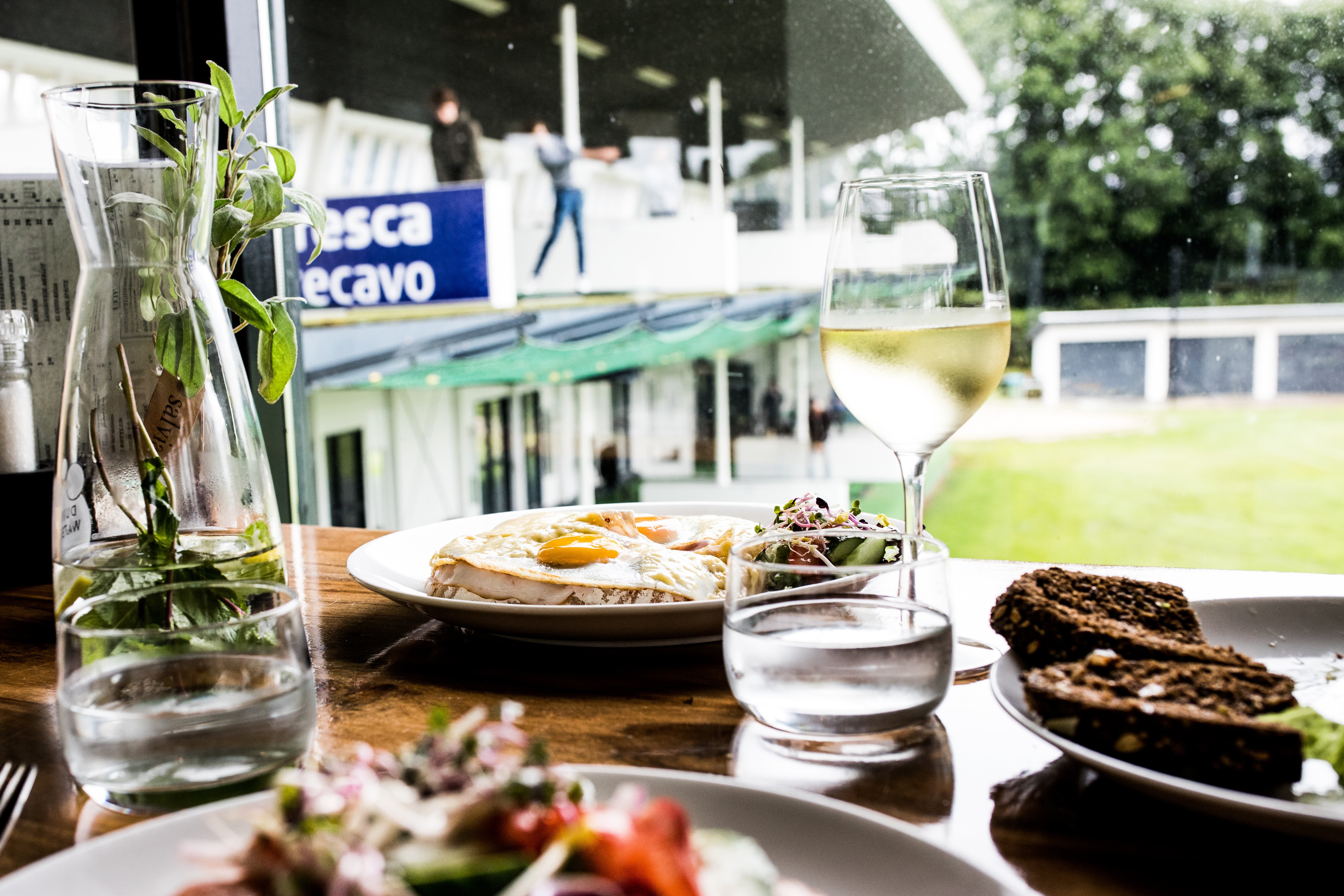 Genieten van een heerlijke lunch met een glas witte wijn en uitzicht op de driving range bij Dekker Warmond.